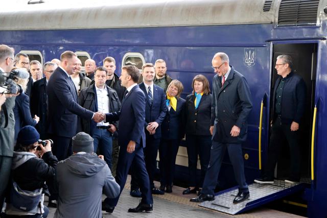 TOPSHOT - An official greets France's President Emmanuel Macron (L), Germany's Chancellor Friedrich Merz (C) and Britain's Prime Minister Keir Starmer (R) as they arrive at Kyiv railway station on May 10, 2025, ahead of a gathering of European leaders in the Ukranian capital. The leaders of Britain, France, Germany and Poland make an unprecedented joint visit to Kyiv on May 10, 2025 for talks with Ukraine's President Volodymyr and to urge Russia to agree a ceasefire, a joint statement said. (Photo by Ludovic MARIN / POOL / AFP)