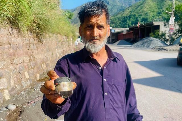A resident shows a fragment of a mortar shell after the cross-border shelling near the Line of Control (LoC) between Pakistan and India in Chakothi village of Pakistan-administered Kashmir on May 10, 2025. Pakistan on May 10 launched counterattacks against India after three of its air bases were struck overnight, as the conflict between the nuclear-armed neighbours spiralled toward full-blown war. (Photo by Sajjad QAYYUM / AFP)