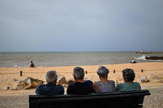 Elderly people sit on a bench in front of the beach during a CHEGA far-right party’s electoral campaign action at Quarteira market in Algarve on April 9, 2025. Snap legislative vote take place in Portugal on May 18, the third national election in three years. In Portugal's tourist-friendly south, the far right is gaining ground. Chega (Enough!) came first in the Algarve province in the last poll, with 27.2 percent of the vote. (Photo by PATRICIA DE MELO MOREIRA / AFP)