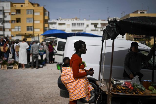 A woman carrying her baby buys during a CHEGA far-right party’s electoral campaign action at Quarteira market in Algarve on April 9, 2025. Snap legislative vote take place in Portugal on May 18, the third national election in three years. In Portugal's tourist-friendly south, the far right is gaining ground. Chega (Enough!) came first in the Algarve province in the last poll, with 27.2 percent of the vote. (Photo by PATRICIA DE MELO MOREIRA / AFP)