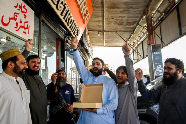 Traders celebrate with sweets outside an electronics showroom in Peshawar on May 10, 2025 after Pakistan launched strikes on India. Pakistan launched counterattacks against India on May 10, after three of its air bases were struck overnight, and as the conflict between the nuclear-armed neighbours spiralled towards a full-blown war that sparked calls against "miscalculation". (Photo by Abdul MAJEED / AFP)