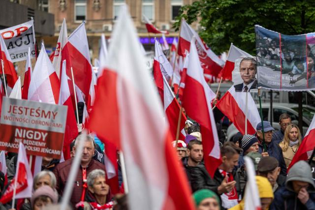 A picture of Karol Nawrocki, candidate for the 2025 Polish presidential election supported by Poland's right-wing Law and Justice (PiS) party, is seen among polish national flags as right wing supporters take part in an anti-migration protest in Warsaw on May 10, 2025, a week ahead of the first round of the Polish presidential election. (Photo by Wojtek RADWANSKI / AFP)