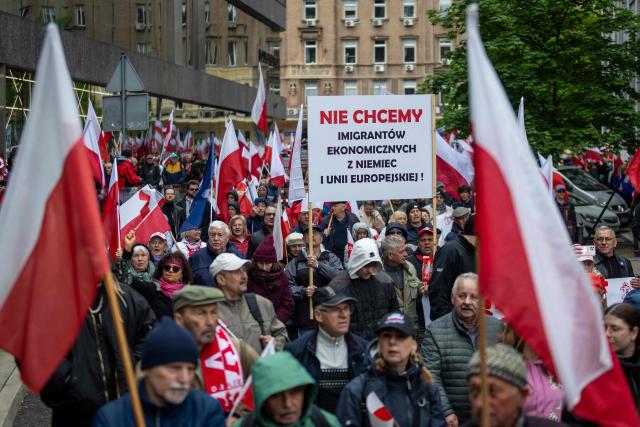 People hold a banner reading "We Don't Want Economical Migrants from Germany and European Union" as they take part in an anti-migration protest in Warsaw on May 10, 2025, a week ahead of the first round of the Polish presidential election. (Photo by Wojtek RADWANSKI / AFP)