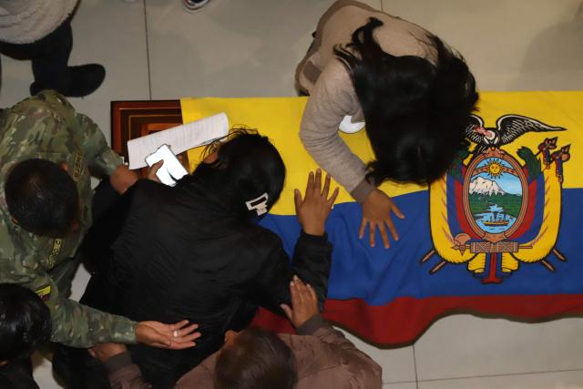 Relatives react in front of one of the coffins with the mortal remains of the 11 soldiers killed on the eve, during their wake at the Eloy Alfaro Military College in Quito on May 10, 2025. Ecuador declared three days of national mourning over the deaths of 11 soldiers who the army said were killed by dissident FARC guerrillas in an ambush in Alto Punino, near the Colombian border. The attack comes amid a spike in violence in both nations linked to the trafficking of cocaine produced in Colombia and exported through Ecuadorean ports to the United States and Europe. (Photo by ARMANDO PRADO / AFP)