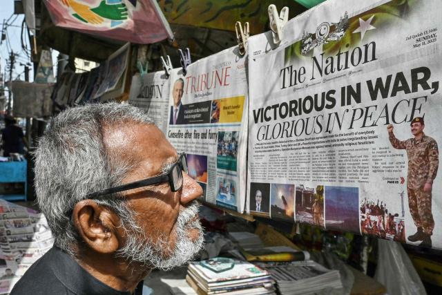 A resident reads a morning English newspaper on a roadside stall in Karachi on May 11, 2025. India and Pakistan traded accusations of ceasefire violations early on May 11, hours after US President Donald Trump announced that the nuclear-armed neighbours had stepped back from the brink of full-blown war. (Photo by Asif HASSAN / AFP)