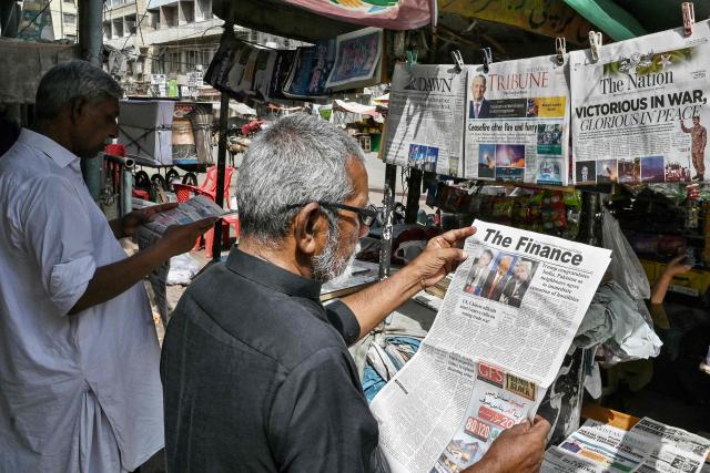 Residents read morning newspapers at a roadside stall in Karachi on May 11, 2025. India and Pakistan traded accusations of ceasefire violations early on May 11, hours after US President Donald Trump announced that the nuclear-armed neighbours had stepped back from the brink of full-blown war. (Photo by Asif HASSAN / AFP)