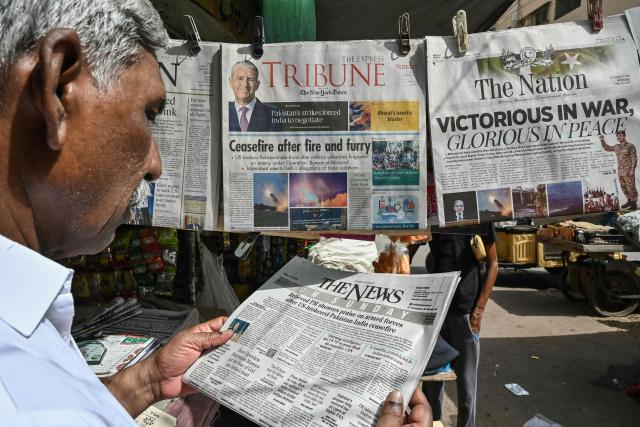 A resident reads a morning English newspaper on a roadside stall in Karachi on May 11, 2025. India and Pakistan traded accusations of ceasefire violations early on May 11, hours after US President Donald Trump announced that the nuclear-armed neighbours had stepped back from the brink of full-blown war. (Photo by Asif HASSAN / AFP)