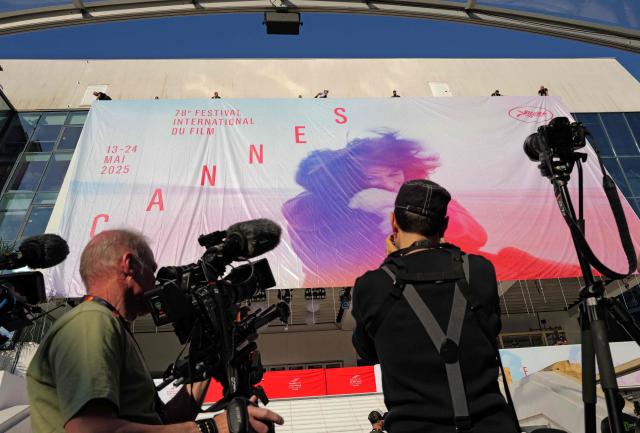 Workers install the official poster of the 78th Cannes Film Festival on the facade of the Palais des Festivals in Cannes, south-eastern France, on May 11, 2025. The 78th Cannes Film Festival will take place from May 13 to May 24, 2025. (Photo by Valery HACHE / AFP)