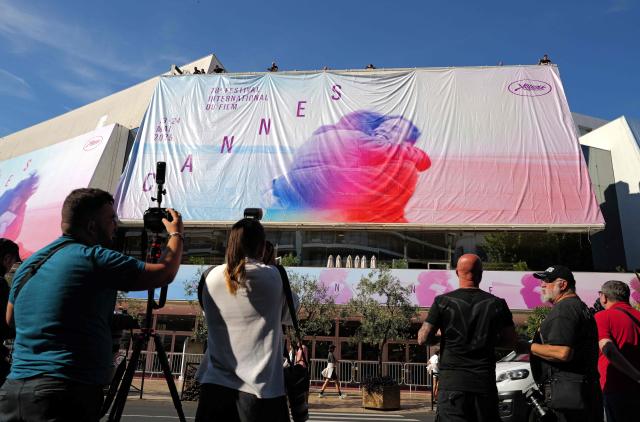 Workers who install the official posters of the 78th Cannes Film Festival on the facade of the Palais des Festivals in Cannes, south-eastern France, on May 11, 2025. The 78th Cannes Film Festival will take place from May 13 to May 24, 2025. (Photo by Valery HACHE / AFP)