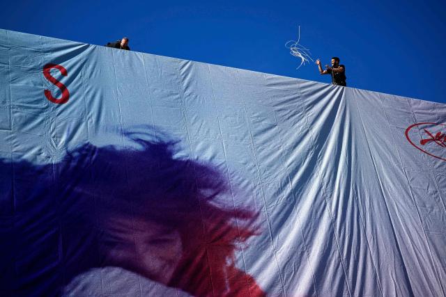 Workers hang the official poster of the 78th Cannes Film Festival on the facade of the Palais des Festivals in Cannes, south-eastern France, on May 11, 2025. Cannes Film festival will take place from May 13 to May 24. (Photo by Valery HACHE / AFP)