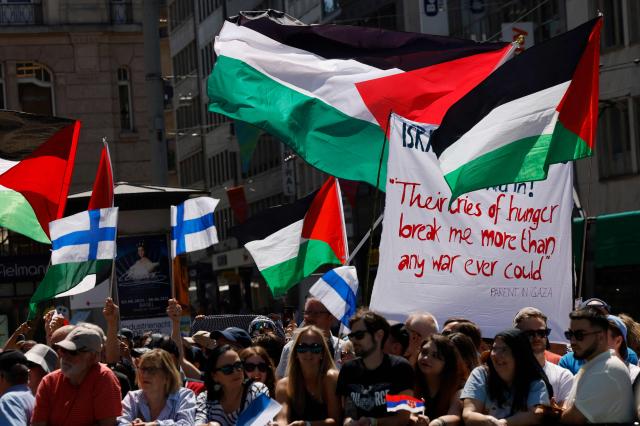 Protestors hold Palestinian and Finnish flags and a banner as they attend a demonstration against Israel's candidate during the Eurovision Song Contest 2025 opening ceremony in Basel on May 11, 2025. (Photo by Stefan Wermuth / AFP)