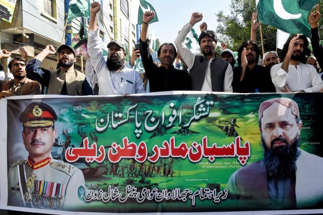 People shout slogans and carry a banner with portraits of Pakistan's Chief of Army Staff General Syed Asim Munir (L) and Jhalawan Awami Panel (JAP) leader Mir Shafiq-ur Rehman Mengal during a rally after Pakistan-India ceasefire in Quetta on May 11, 2025. A ceasefire appeared to hold on May 11, between India and Pakistan, hours after the nuclear-armed rivals accused each other of violating a truce that brought them back from the brink of all-out war. (Photo by Banaras KHAN / AFP)
