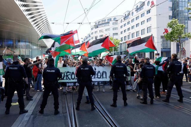 Police officers stand guard in front of protestors waving Palestinian flags as they take part in a demonstration against Israel's candidate and during the Eurovision Song Contest 2025 opening ceremony in Basel on May 11, 2025. (Photo by Stefan Wermuth / AFP)