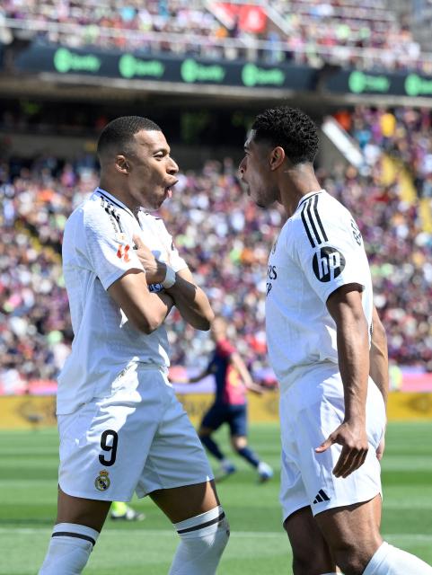 Real Madrid's French forward #09 Kylian Mbappe (L) celebrates with Real Madrid's English midfielder #05 Jude Bellingham after converting a penalty to score their first goal during the Spanish league football match between FC Barcelona and Real Madrid CF at Estadi Olimpic Lluis Companys in Barcelona, on May 11, 2025. (Photo by Josep LAGO / AFP)