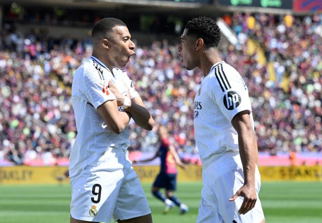 Real Madrid's French forward #09 Kylian Mbappe (L) celebrates with Real Madrid's English midfielder #05 Jude Bellingham after converting a penalty to score their first goal during the Spanish league football match between FC Barcelona and Real Madrid CF at Estadi Olimpic Lluis Companys in Barcelona, on May 11, 2025. (Photo by Josep LAGO / AFP)