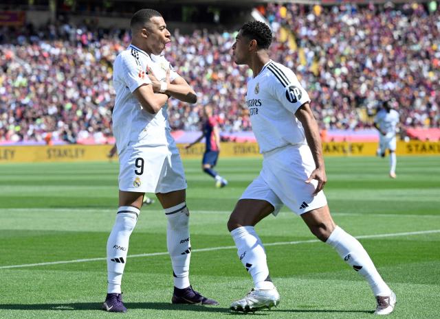 Real Madrid's French forward #09 Kylian Mbappe (L) celebrates with Real Madrid's English midfielder #05 Jude Bellingham after converting a penalty to score their first goal during the Spanish league football match between FC Barcelona and Real Madrid CF at Estadi Olimpic Lluis Companys in Barcelona, on May 11, 2025. (Photo by Josep LAGO / AFP)
