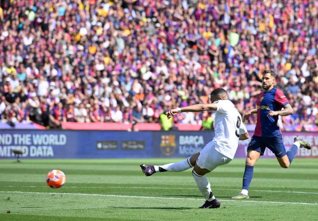 Real Madrid's French forward #09 Kylian Mbappe shoots to score their second goal during the Spanish league football match between FC Barcelona and Real Madrid CF at Estadi Olimpic Lluis Companys in Barcelona, on May 11, 2025. (Photo by Josep LAGO / AFP)