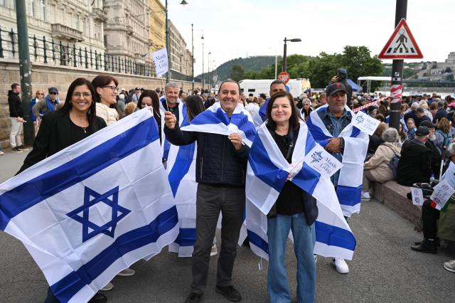 Participants in the 'March of the Living' hold Israeli flags on the oldest Hungarian bridge the 'Lanchid' (Chain Bridge) on May 11, 2025, in Budapest. The 'March of the Living' commemorates the Holocaust victims who were deported to the concentration camps by the Nazis. (Photo by Attila KISBENEDEK / AFP)