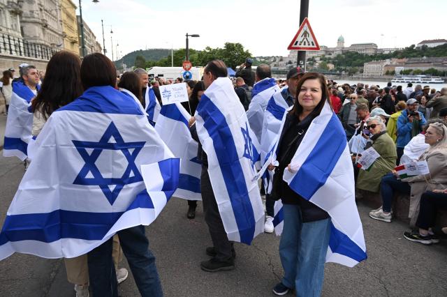 Participants in the 'March of the Living' hold Israeli flags on the oldest Hungarian bridge the 'Lanchid' (Chain Bridge) on May 11, 2025, in Budapest. The 'March of the Living' commemorates the Holocaust victims who were deported to the concentration camps by the Nazis. (Photo by Attila KISBENEDEK / AFP)