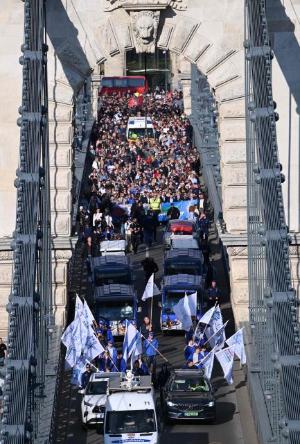 Participants in the 'March of the Living' cross the oldest Hungarian bridge the 'Lanchid' (Chain Bridge) on May 11, 2025, in Budapest. The 'March of the Living' commemorates the Holocaust victims who were deported to the concentration camps by the Nazis. (Photo by Attila KISBENEDEK / AFP)