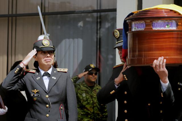 A relative of Lieutenant Jorge Andrade Bastidas, one of the 11 soldiers killed on May 9, salutes as his coffin is carried away after the funeral mass at the Eloy Alfaro Military College in Quito on May 11, 2025. Ecuador declared three days of national mourning over the deaths of 11 soldiers who the army said were killed by dissident FARC guerrillas in an ambush in Alto Punino, near the Colombian border amid a spike in violence linked to the trafficking of cocaine. (Photo by ARMANDO PRADO / AFP)