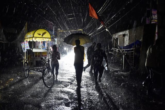 TOPSHOT - A man carrying an umbrella is silhouetted during rainfall in Jalandhar on May 11, 2025. (Photo by Shammi MEHRA / AFP)