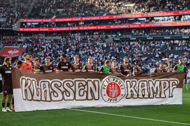 St. Pauli players hold a banner which reads "class struggle" the German first division Bundesliga football match between Eintracht Frankfurt and FC St. Pauli in Frankfurt, western Germany, on May 11, 2025. (Photo by Daniel ROLAND / AFP) / DFL REGULATIONS PROHIBIT ANY USE OF PHOTOGRAPHS AS IMAGE SEQUENCES AND/OR QUASI-VIDEO