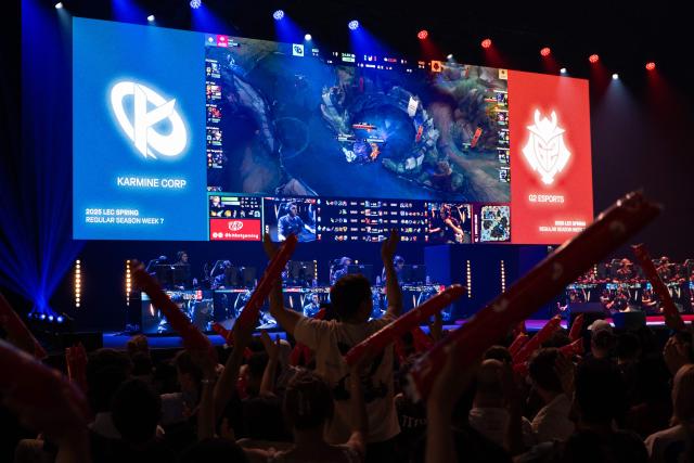 Supporters cheer as Karmine Corp's players (L) compete against the G2 eSports' players in the League of Legends EMEA Championship (LEC) Roadtrip - eSports competition at Les Arenes in Evry-Courcouronnes, suburb of Paris, on May 11, 2025. (Photo by LEO VIGNAL / AFP)