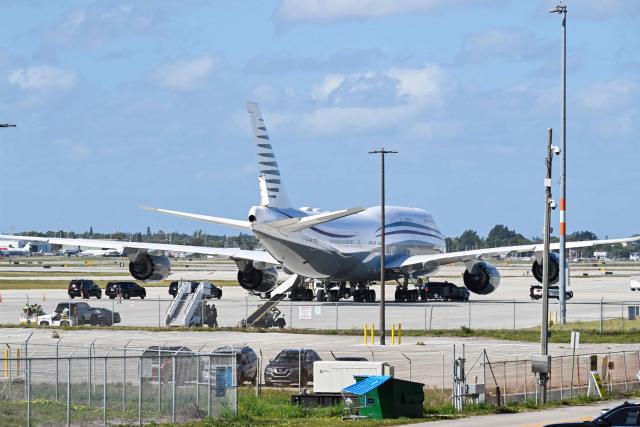 In this February 15, 2025 photo the motorcade of US President Donald Trump is parked next to an almost 13 year old Boeing 747 sitting on the tarmac of Palm Beach International airport on February 15, 2025. Donald Trump plans to accept a luxury Boeing jet from the Qatari royal family for use as Air Force One and then continue flying in it after his tenure, despite strict rules on US presidential gifts, media reported May 11, 2025. Calling the plane a "flying palace," ABC News, which first reported the story, said the Boeing 747-8 jumbo jet would possibly be the most expensive gift ever received by the American government. (Photo by ROBERTO SCHMIDT / AFP)