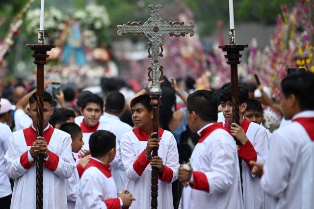 Acolytes carry a cross as they take part in the Panchimalco Flower and Palm Festival procession in Panchimalco, El Salvador on May 11, 2025. (Photo by Marvin RECINOS / AFP)