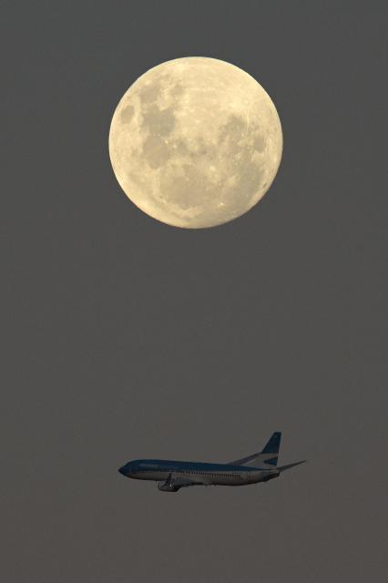 An Aerolineas Argentinas Airlines airplane passes by the almost full moon after taking off from Jorge Newbery Airport in Buenos Aires on May 11, 2025. (Photo by JUAN MABROMATA / AFP)