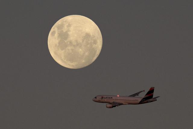 A LATAM Airlines airplane passes by the almost full moon after taking off from Jorge Newbery Airport in Buenos Aires on May 11, 2025. (Photo by JUAN MABROMATA / AFP)