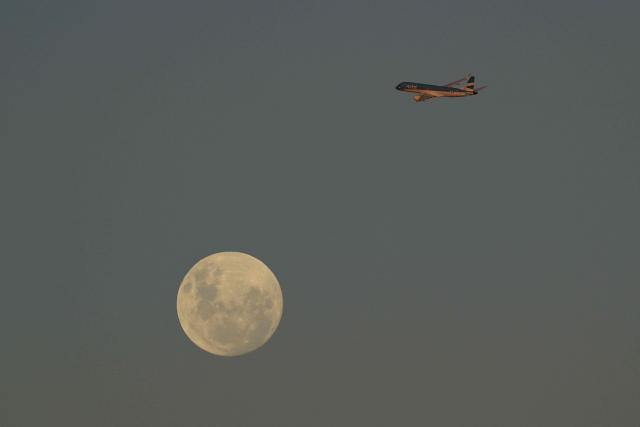 An Austral Airlines airplane passes by the almost full moon after taking off from Jorge Newbery Airport in Buenos Aires on May 11, 2025. (Photo by JUAN MABROMATA / AFP)