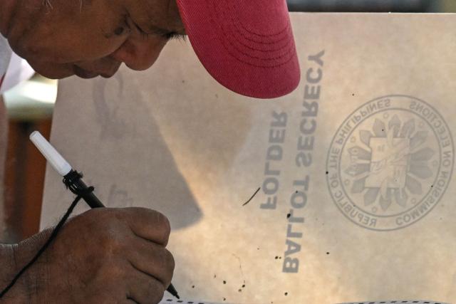 A man votes at a polling station during mid-term elections in Manila on May 12, 2025. Millions of Filipinos headed to the polls May 12 in a mid-term election widely seen as a referendum on the explosive feud between President Ferdinand Marcos and impeached Vice President Sara Duterte. (Photo by Jam STA ROSA / AFP)