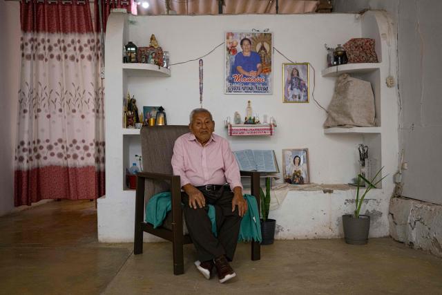 Catalino Puican, 93, poses for a picture next to an altar at his home in the Eten district, Lambayeque region, northern Peru on May 10, 2025. In the small town of Eten the faithful flock every year to celebrate the miracle of the Divine Child, a sacred phenomenon not yet recognised by the Vatican. The election of Leo XIV, former bishop of the diocese, has revived hopes for official recognition, as well as for the construction of a sanctuary worthy of this Eucharistic miracle, the only one of its kind reported in Peru. (Photo by ERNESTO BENAVIDES / AFP)