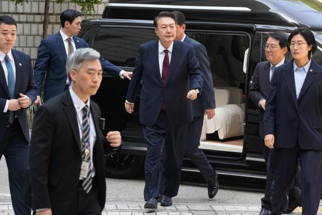 South Korea's ousted President Yoon Suk Yeol (C), who is facing charges of orchestrating a rebellion when he declared martial law on December 3, 2024, arrives to attend his trial at the Seoul Central District Court in Seoul on May 12, 2025. South Korea's former president Yoon Suk Yeol appeared in court May 12 for the third hearing of his criminal trial to defend himself against insurrection charges over his short-lived declaration of martial law. (Photo by Ahn Young-joon / POOL / AFP)