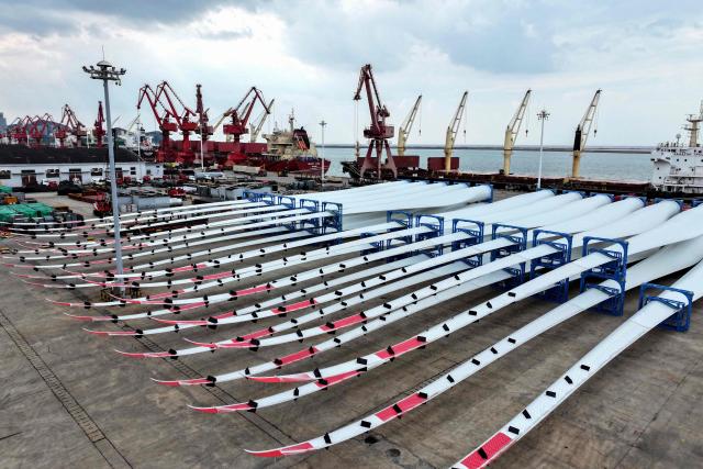 This photo taken on May 10, 2025 shows wind turbine blades waiting to be loaded onto a ship for export at the port in Lianyungang, in China’s eastern Jiangsu province. (Photo by AFP) / China OUT