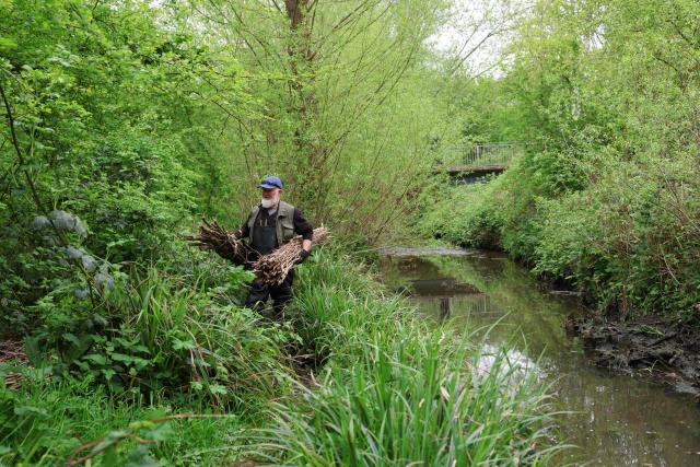 A volunteer carries materials to be used in constructing a natural flood management feature on the Saffron Brook in Leicester, central England on April 24, 2025. Leicester, like many other cities in the UK, has experienced several intense rainfall events in recent years, which have caused significant damage. Alert to climate change, which intensifies these events, authorities are strengthening their defences and turning to solutions more sympathetic with the environment. (Photo by Darren Staples / AFP) / TO GO WITH AFP STORY By Marie HEUCLIN