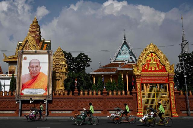 Tourists ride rickshaws, known locally as "cyclos", along a street in front of a pagoda in Phnom Penh on May 12, 2025. (Photo by TANG CHHIN Sothy / AFP)