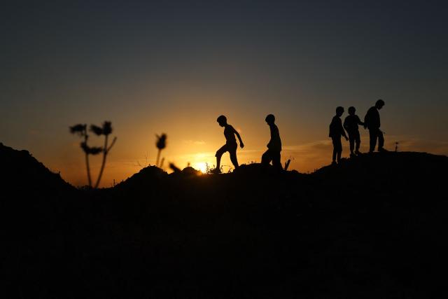 Palestinian children play in a field in Deir el-Balah in the central Gaza Strip at sunset on May 12, 2025. (Photo by Eyad BABA / AFP)