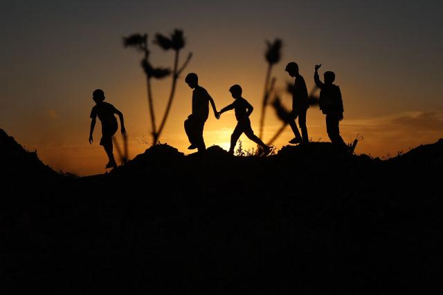 Palestinian children play in a field in Deir el-Balah in the central Gaza Strip at sunset on May 12, 2025. (Photo by Eyad BABA / AFP)