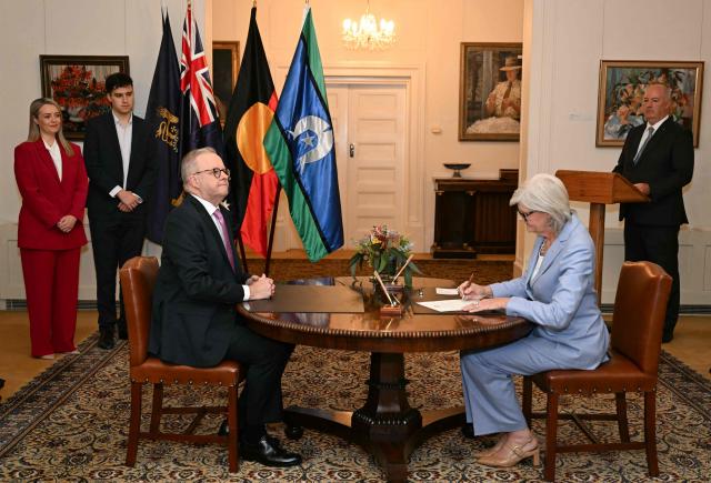Australia's re-elected Prime Minister Anthony Albanese (L) looks on after taking an oath in front of Australia's Governor General Sam Mostyn (R) signing an official document at Government House in Canberra on May 13, 2025. (Photo by Saeed KHAN / AFP)