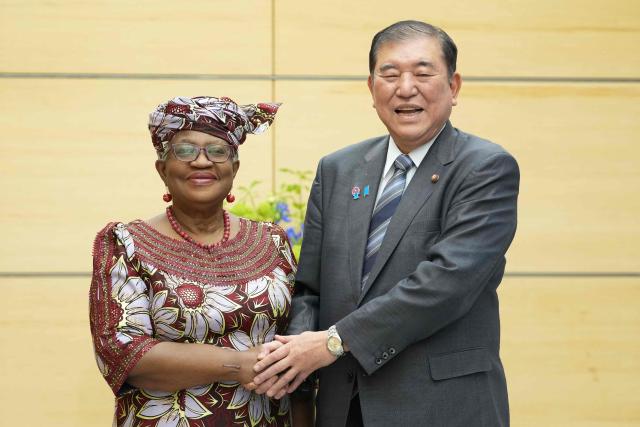World Trade Organization (WTO) Director-General Ngozi Okonjo-Iweala (L) shakes hands with Japan's Prime Minister Shigeru Ishiba at the latter's office in Tokyo on May 13, 2025. (Photo by Kazuhiro NOGI / POOL / AFP)