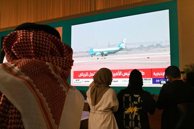 People watch a live coverage at the Ministry of Media as the plane carrying US President Donald Trump lands in Riyadh on May 13, 2025. (Photo by Giuseppe CACACE / AFP)