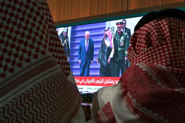 People watch a live coverage at the Ministry of Media as the US President Donald Trump walk with Saudi Crown Prince Mohammed bin Salman upon landing in Riyadh on May 13, 2025. (Photo by Giuseppe CACACE / AFP)