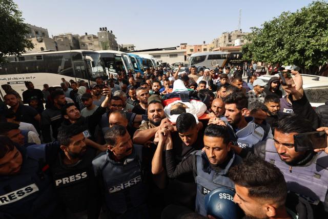 EDITORS NOTE: Graphic content / TOPSHOT - Palestinian journalists walk in the funeral procession of their colleague Hassan Aslih, killed at dawn in an Israeli strike which hit the surgeries building at the Nasser hospital, in Khan Yunis in the southern Gaza Strip on May 13, 2025. The Israeli military said it struck a Gaza hospital "housing Hamas militants" in a raid on May 13 which, according to the Palestinian group, killed the journalist who had been wounded in an Israeli attack last month and a number of civilians. (Photo by Eyad BABA / AFP)