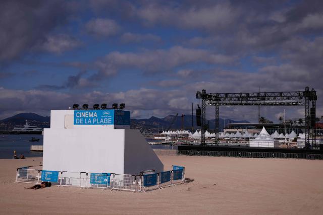 A lone beachgoer sleeps by the "Cinema de la Plage", an outdoor cinema set up on the Plage Mace beach, on the opening day of the 78th edition of the Cannes Film Festival in Cannes, southern France, on May 13, 2025. (Photo by Ian LANGSDON / AFP)