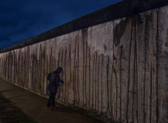 (FILES) A person touches a segment of the Berlin wall at the Bernauerstrasse wall memorial on the 30th anniversary of the fall of the Berlin Wall, on November 9, 2019 in Berlin. Already presented at the beginning of the year in Madrid, an exhibition opening on May 14, 2025 traces through some 200 objects, photographs, documents, films, and testimonies the history of this emblematic wall of the bipolar world resulting from World War II, from its construction to its destruction on November 9, 1989. (Photo by John MACDOUGALL / AFP)