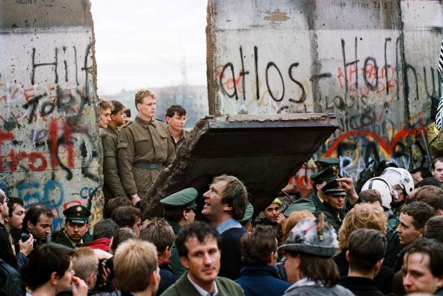 (FILES) West Berliners crowd in front of the Berlin Wall early 11 November 1989 as they watch East German border guards demolishing a section of the wall in order to open a new crossing point between East and West Berlin, near the Potsdamer Square. Two days before, Gunter Schabowski, the East Berlin Communist party boss, declared that starting from midnight, East Germans would be free to leave the country, without permission, at any point along the border, including the crossing-points through the Wall in Berlin. The Berlin concrete wall was built by the East German government in August 1961 to seal off East Berlin from the part of the city occupied by the three main Western powers to prevent mass illegal immigration to the West. According to the "August 13 Association" which specialises in the history of the Berlin Wall, at least 938 people - 255 in Berlin alone - died, shot by East German border guards, attempting to flee to West Berlin or West Germany. Already presented at the beginning of the year in Madrid, an exhibition opening on May 14, 2025 traces through some 200 objects, photographs, documents, films, and testimonies the history of this emblematic wall of the bipolar world resulting from World War II, from its construction to its destruction on November 9, 1989. (Photo by GERARD MALIE / AFP)
