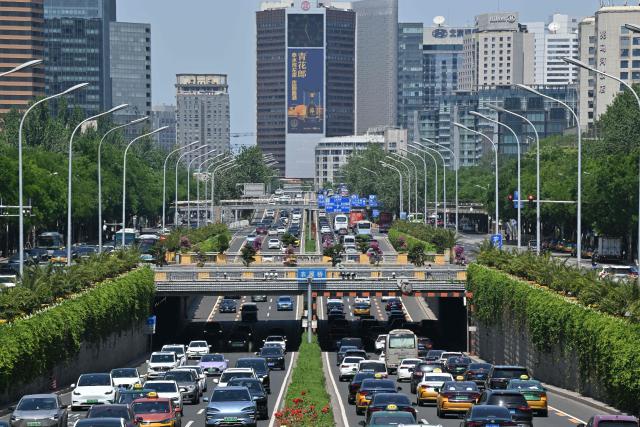 Motorists commute on a road in the Sanlitun business district in Beijing on May 14, 2025. (Photo by ADEK BERRY / AFP)